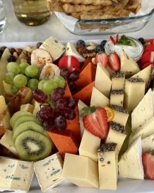 Vielfältige Käseplatte mit Obst, Trauben, Erdbeeren und Nüssen.
